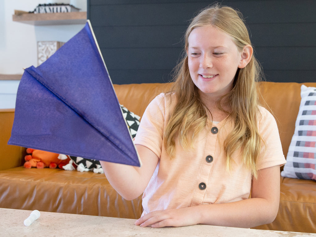 girl holding up the glider she made with the Creating Gliders Kit